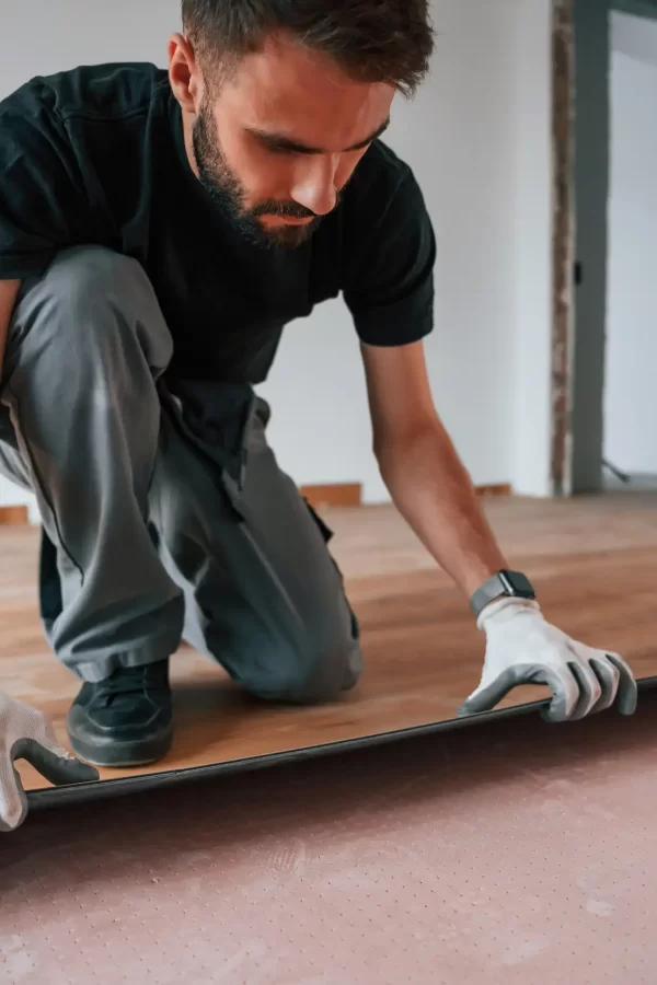 A man installing a laminated wood flooring inside the house.